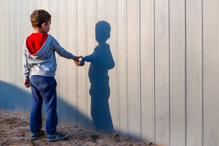 boy and his shadow. Lonely little child playing with his shadow outside. the concept of autism and loneliness. Copy space for your text